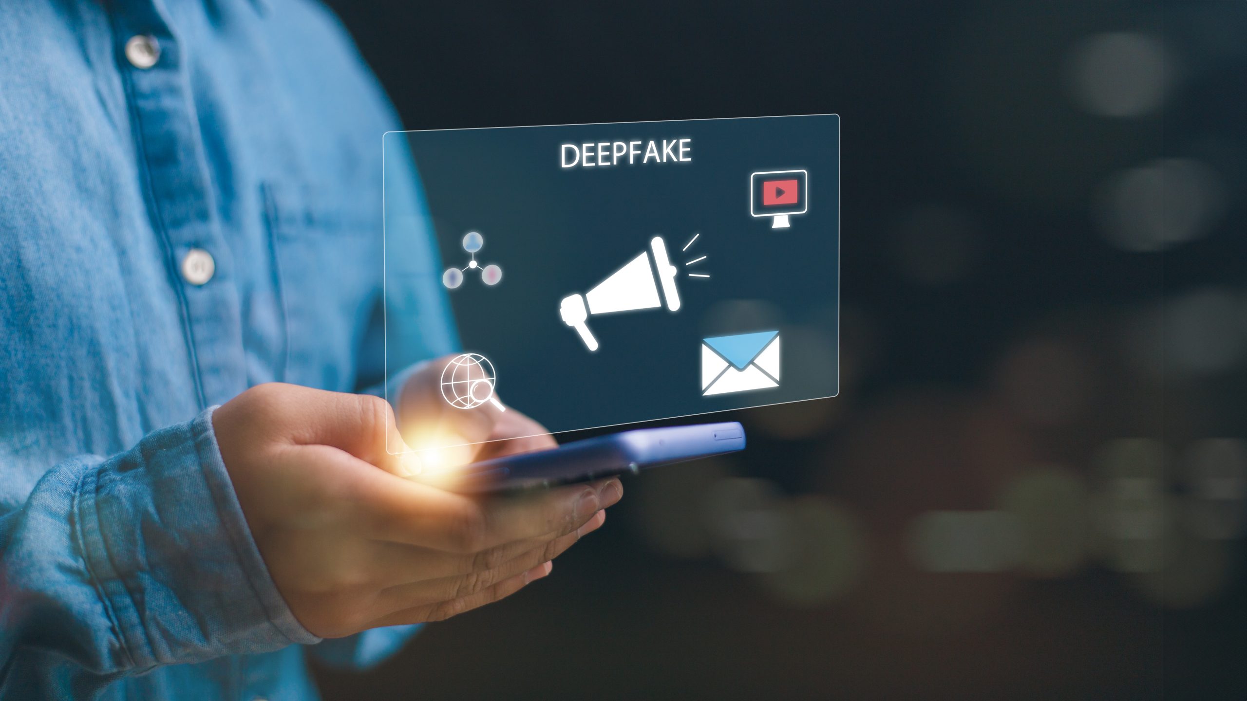 Hands hold smartphone which is projecting a transparent digital screen with symbols that says deepfake.